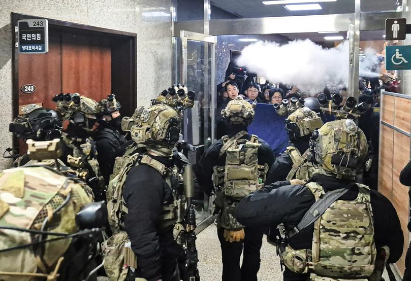 A National Assembly staff sprays fire extinguishers to block soldiers entering the main hall of the National Assembly in Seoul, South Korea, Wednesday, Dec. 4, 2024.