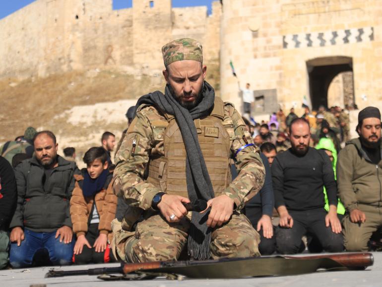 Members of the armed group opposing  former Syrian President Bashar al-Assad's regime perform Islamic prayer at Aleppo Castle after they seized control of much of Aleppo's city center in Syria