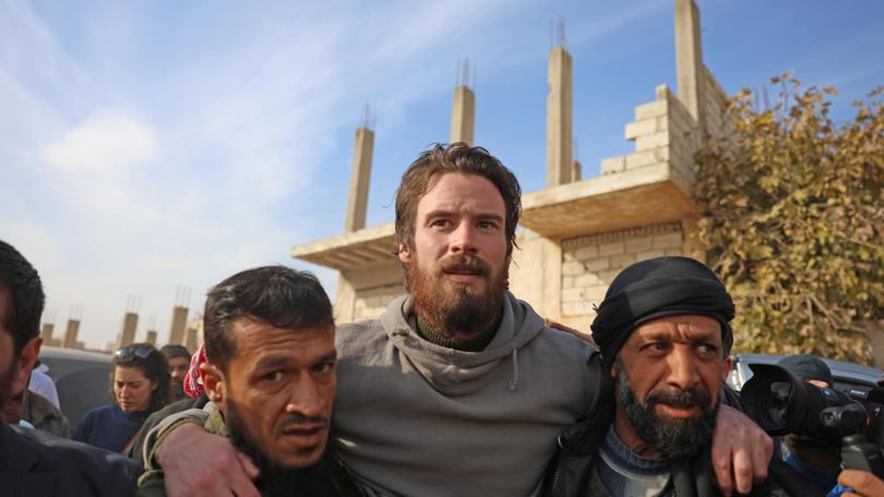 Syrian opposition forces help US citizen Travis Timmerman, centre, who was found by residents in the town of Dhiyabiya.