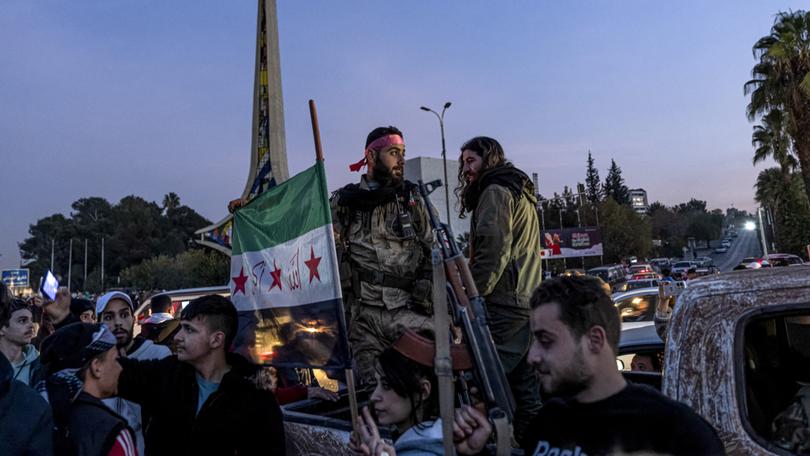 Rebel fighters celebrate with other Syrians after the fall of Bashar al-Assad’s regime, in Damascus, Dec. 9, 2024. 