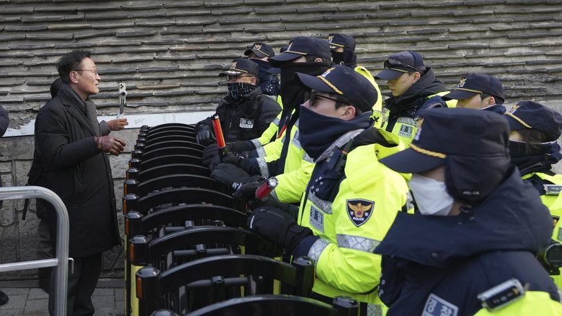 A member of civic rights group is blocked by police officers near South Korea's presidential office.