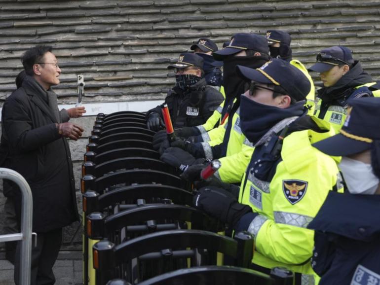 A member of civic rights group is blocked by police officers near South Korea's presidential office.