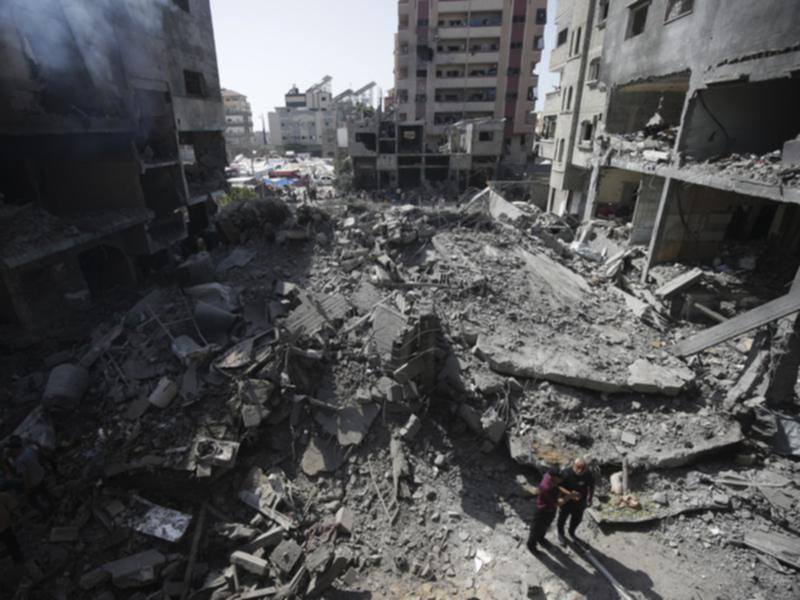 Palestinians look over the aftermath of an air strike on a building in a suburb of Gaza City. 