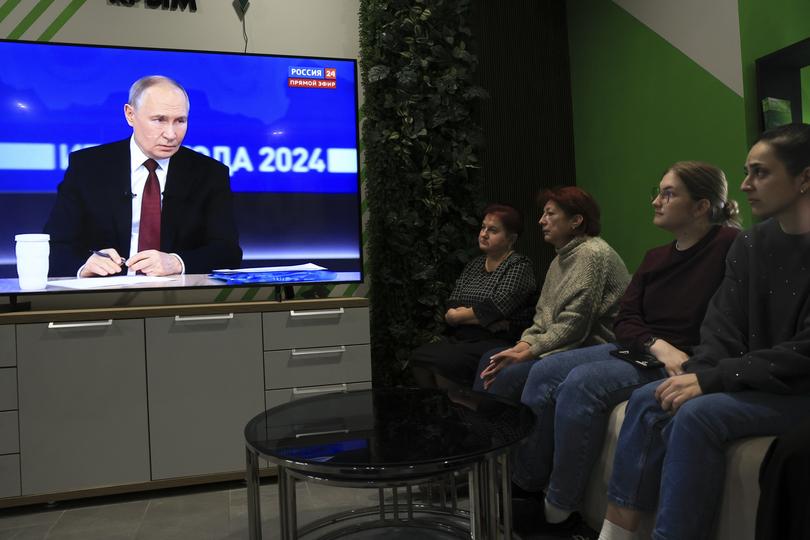 Russian office employees watch Russian President Vladimir Putin's annual news conference.