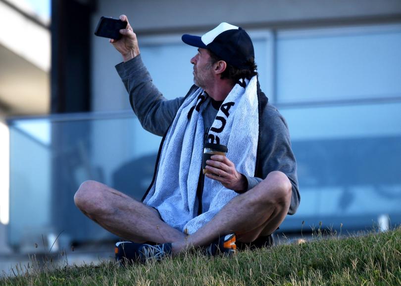 Hugh Jackman on an animated phone call while overlooking Bondi Beach before a gym workout.