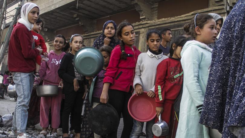 Internally displaced Palestinian children queue to receive food distributed by charitable organisations in the Nasser neighborhood of Gaza City.