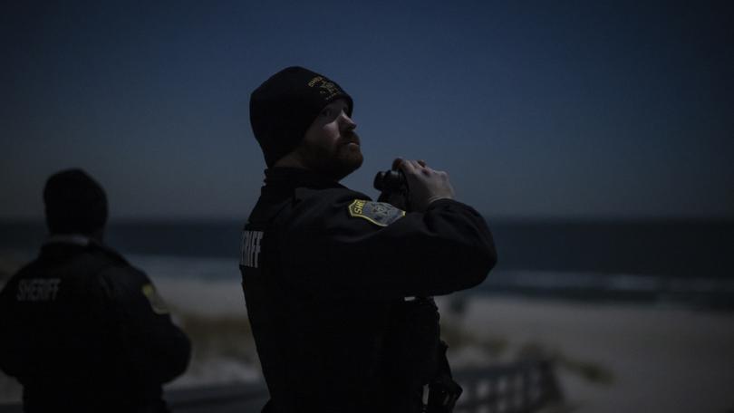 An Ocean County sheriff’ds officer scans the night sky for drones at Island Beach State Park, in Lanoka Harbor, New Jersey. 