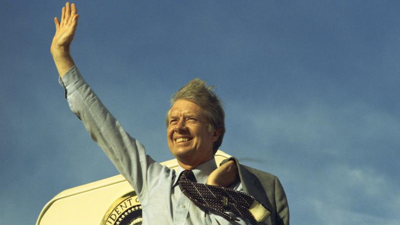 Former US President Jimmy Carter waving atop the steps of Air Force One in 1977.