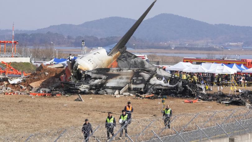 Firefighters and rescue team members work near the wreckage of a passenger plane at Muan International Airport.