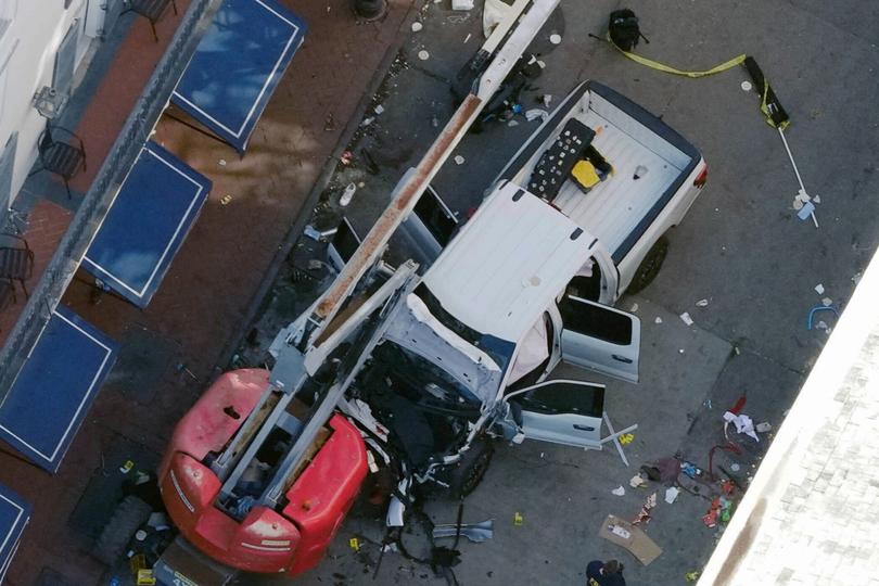 A black flag with white lettering lies on the ground rolled up behind the pickup truck.