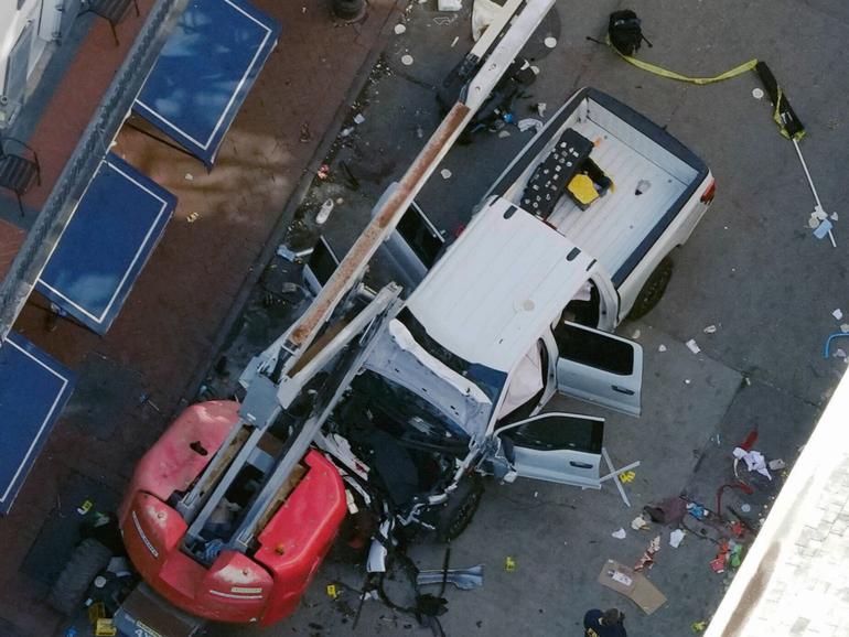 A black flag with white lettering lies on the ground rolled up behind a pickup truck that a man drove into a crowd on Bourbon Street in New Orleans, killing and injuring a number of people, early Wednesday morning, Jan. 1, 2025. 