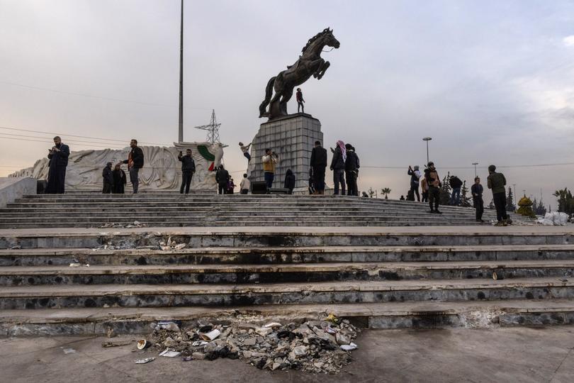 Syrians gather around a statue that depicted Assad’s brother on a horse, blood stains still visible from one of the regime’s final airstrikes, in Aleppo, Syria, Dec. 20, 2024. 