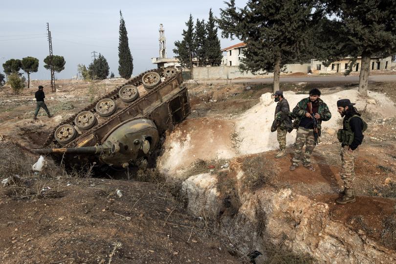 Syrian fighters investigating an overturned tank, left behind after President Bashar al-Assad’s soldiers fought rebels advancing from the north, near a checkpoint on the outskirts of Homs, Syria.