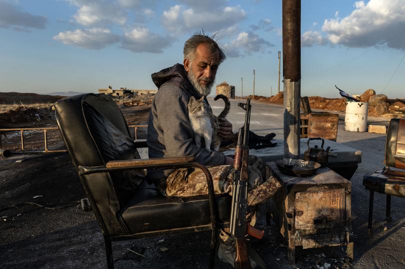 Ali holds a cat in his lap as he mans a checkpoint on the main road leading into the town of Tel Rifaat, Syria, Dec. 13, 2024. Rebels easily toppled Syria’s army and their path to victory is littered with evidence of Syria’s defeated military, reflecting the sizable task of trying to put the country back together. (David Guttenfelder/The New York Times)