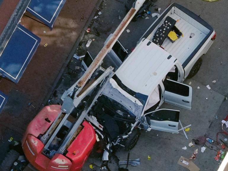 A black flag with white lettering lies on the ground rolled up behind a pickup truck that a man drove into a crowd on Bourbon Street in New Orleans.