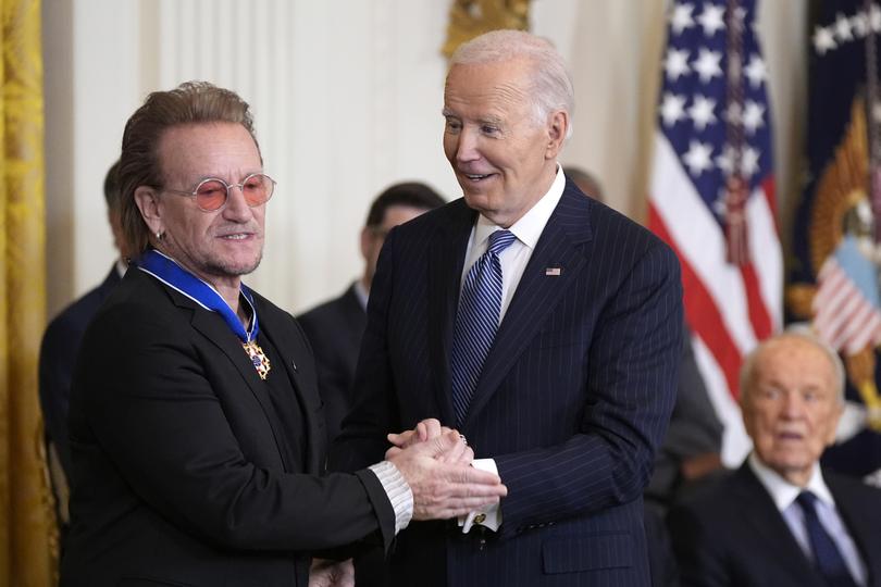 President Joe Biden (r) shakes hands with Bono after presenting him with the Presidential Medal of Freedom.