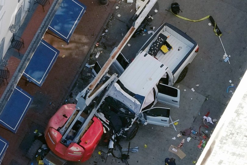 A black flag with white lettering lies on the ground rolled up behind a pickup truck used by the terrorist.