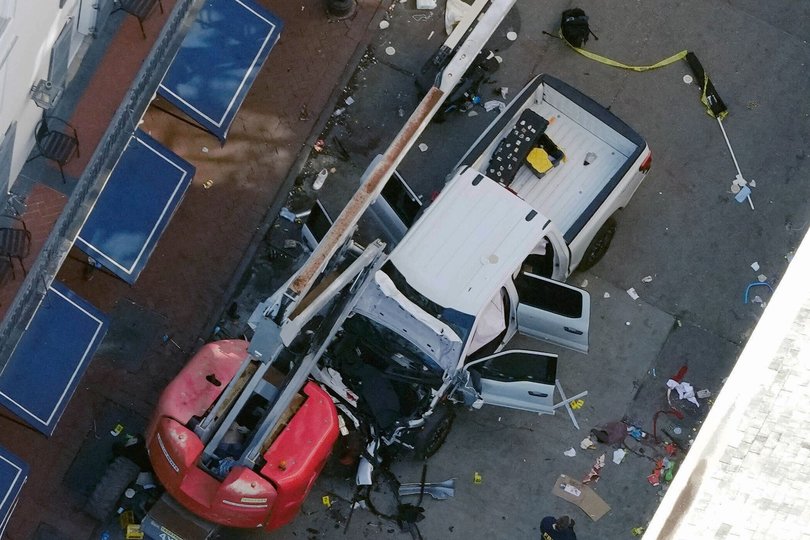 A black flag with white lettering lies on the ground rolled up behind a pickup truck used by the terrorist. 