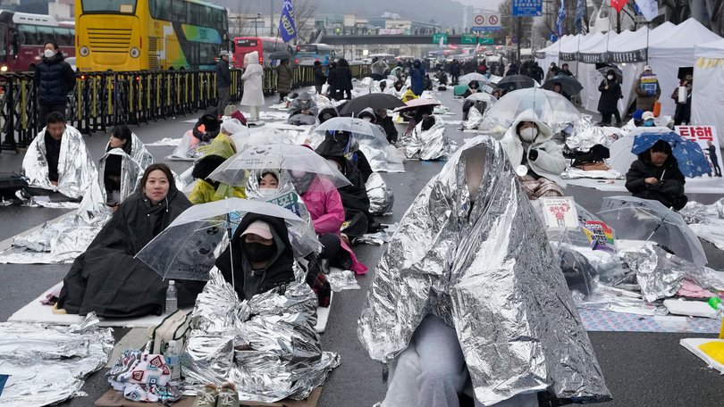 Protesters wrapped in silver-coated mats to protect against the cold wait for a rally demanding the arrest of impeached South Korean President Yoon Suk Yeol in Seoul.