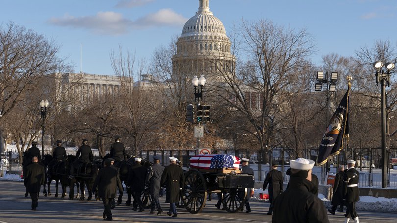 The flag-draped casket of President Jimmy Carter moves toward the US Capitol on a horse-drawn caisson at Constitution Avenue on Capitol Hill.