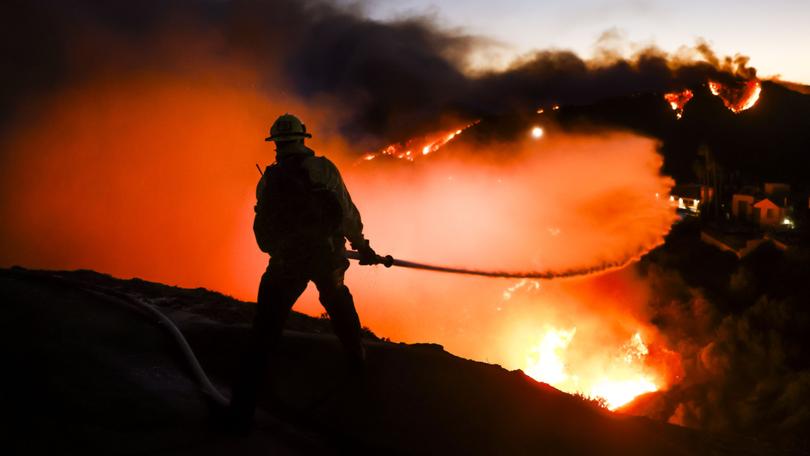 A Los Angeles County firefighter battles the Palisades wildfire.