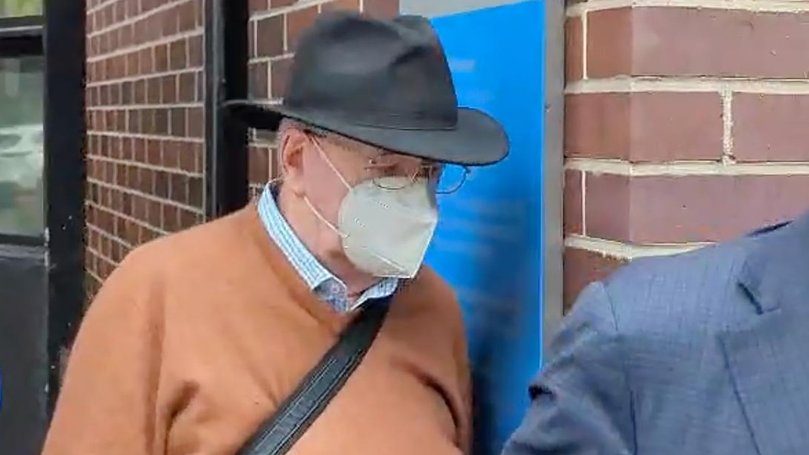 Ex-priest Guy Norman Hartcher tried to hide his face behind a hat and face mask outside court.