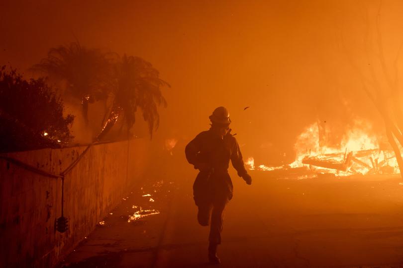 A photographer runs past burning houses in Pacific Palisades.