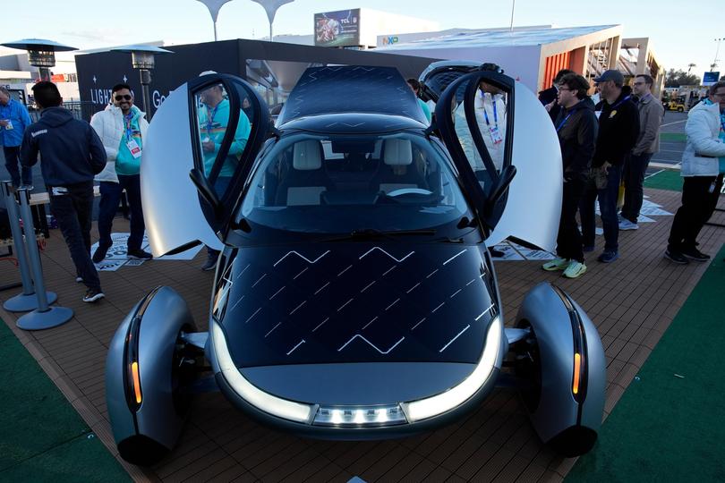 People look at a prototype solar electric vehicle by Aptera Motors.