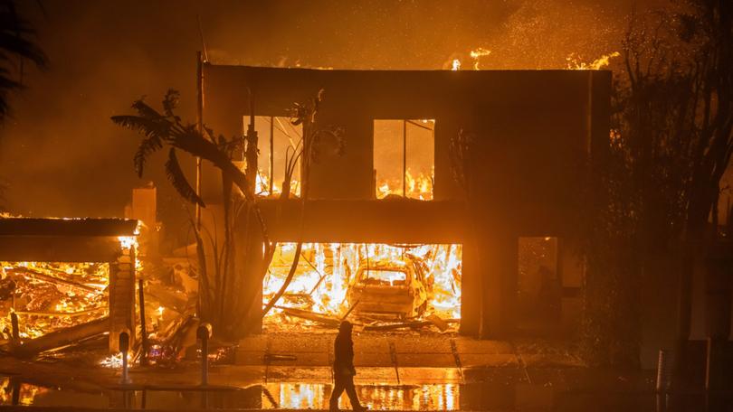 A firefighter watches the flames from the Palisades Fire burning homes on the Pacific Coast Highway amid a powerful windstorm on January 8, 2025 in Los Angeles, California.  