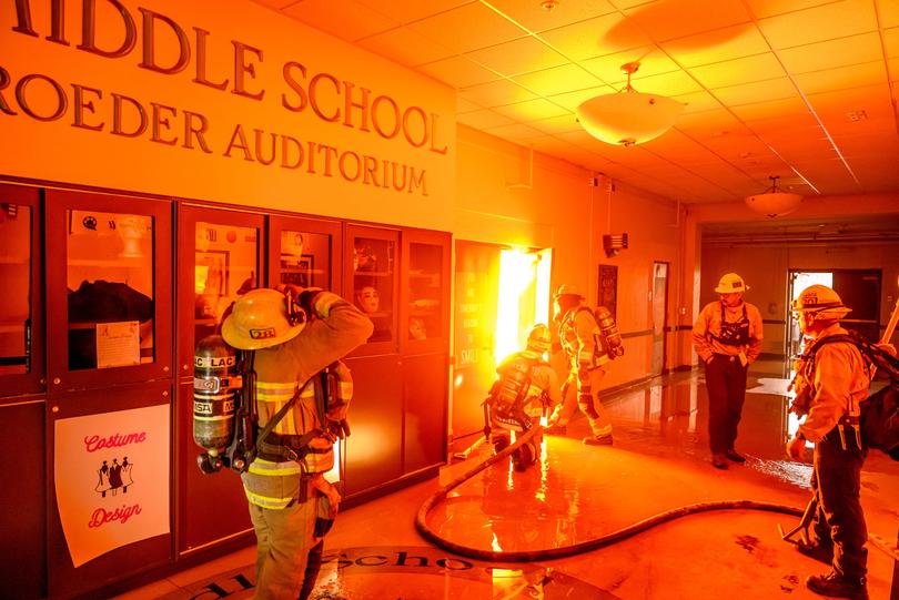 Firefighters prepare to fight flames from inside Eliot Arts Magnet Middle School auditorium as the school burns during the Eaton fire in the Altadena area of Los Angeles county, California on January 8, 2025. 