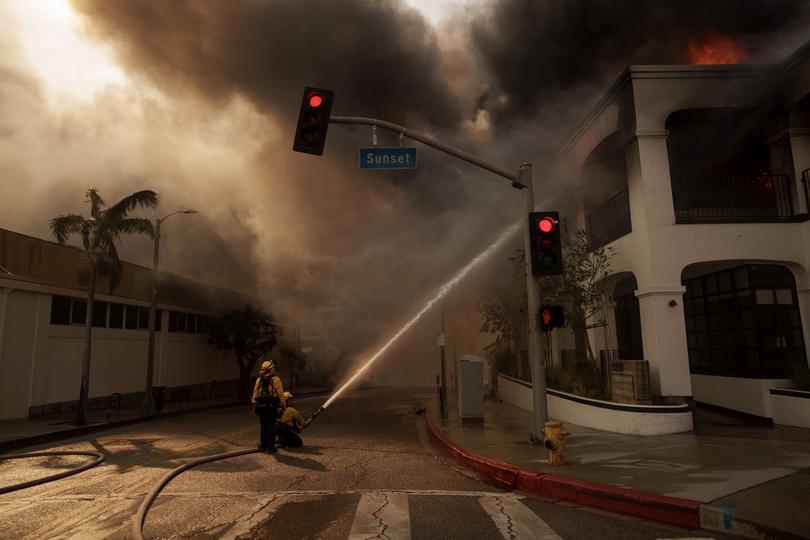 Firefighters spray flames from the Palisades Fire burning a business on January 8, 2025 in the Pacific Palisades neighbourhood of Los Angeles, California. 