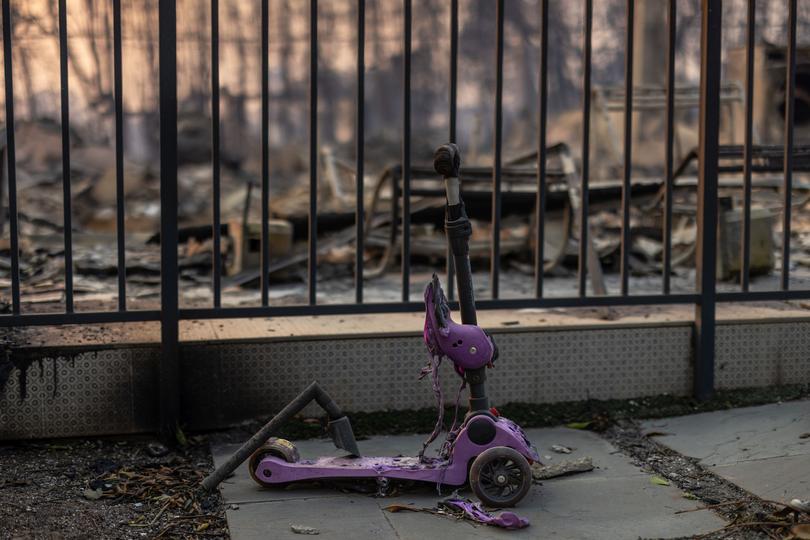 A child's scooter is melted in front of a home destroyed in the Palisades Fire.