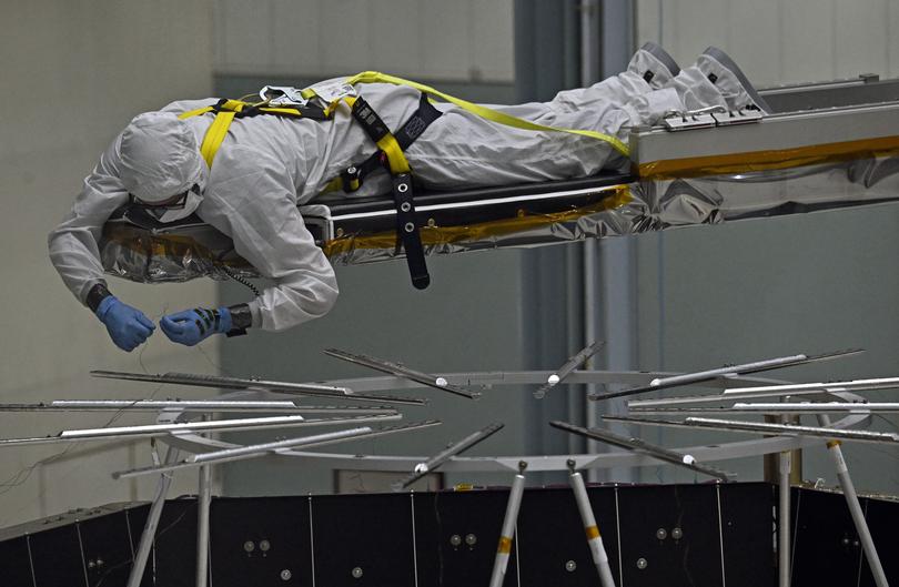 A worker in a clean suit labours on the assembly of the Roman Telescope. 