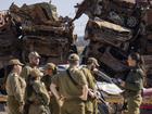 Israeli soldiers look at charred vehicles burned in the Oct. 7 , 2023, cross-border attacks by Hamas militants outside the town of Netivot.