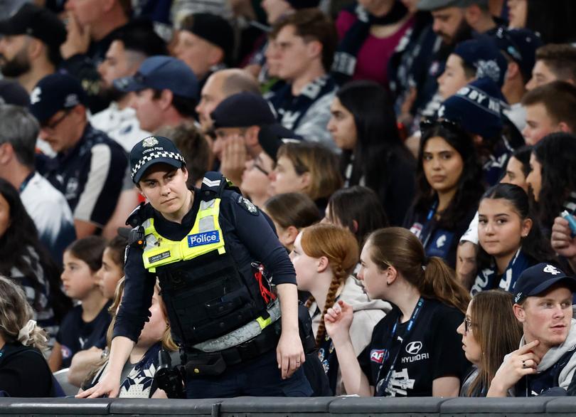 Police patrol the crowd after a goal umpire had to leave the field when he was hit in the head with a water bottle. 