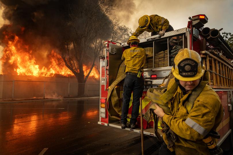 Firefighters work to extinguish a fire at the Altadena Golf Course on Thursday.