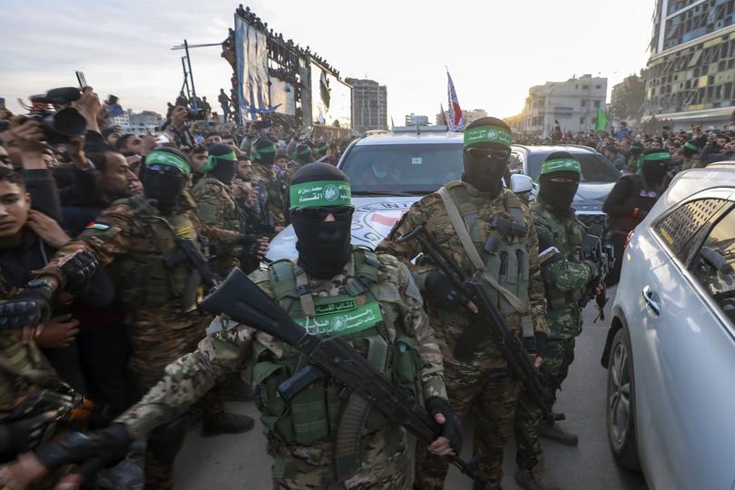 Hamas fighters escort a Red Cross vehicle to collect Israeli hostages released after a ceasefire agreement between Israel and Hamas took effect, in Gaza City.