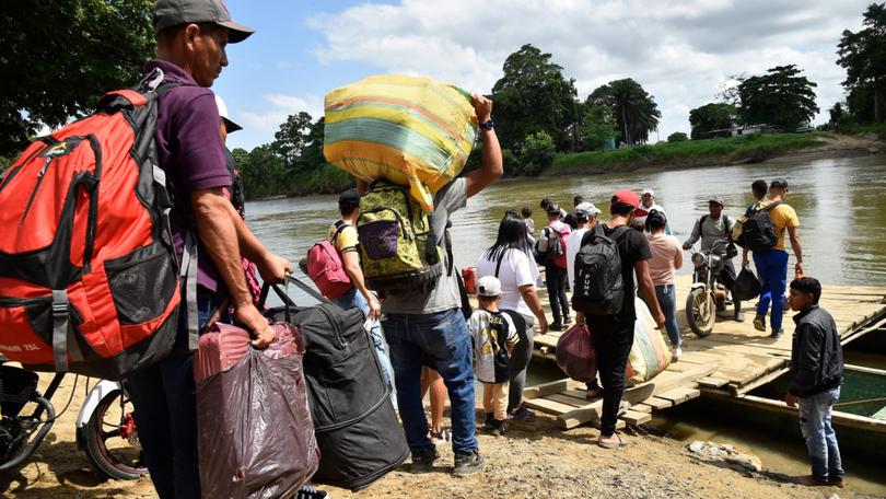 Displaced people from recent clashes between armed groups board canoes to cross the Tarra River, which divides Colombia and Venezuela, in Tibu.