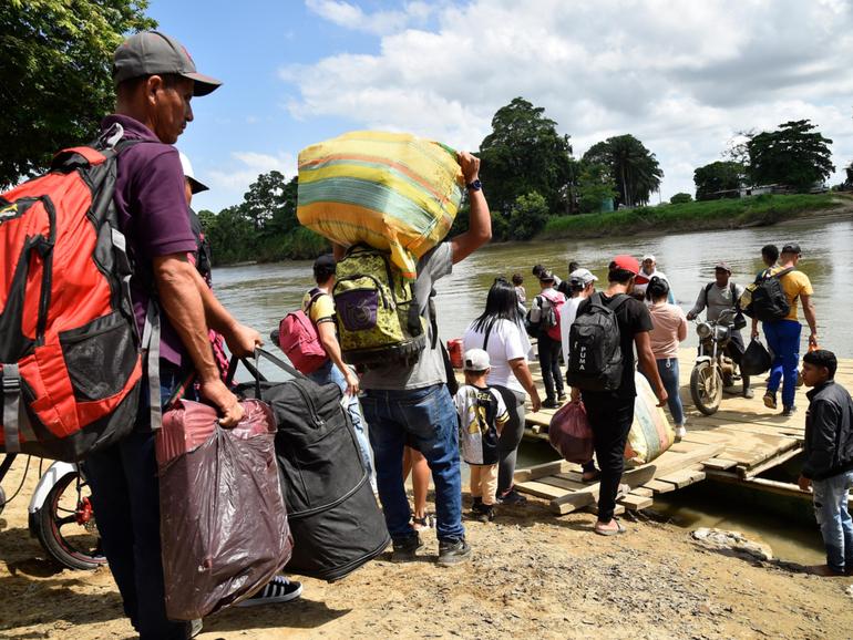 Displaced people from recent clashes between armed groups board canoes to cross the Tarra River, which divides Colombia and Venezuela, in Tibu.