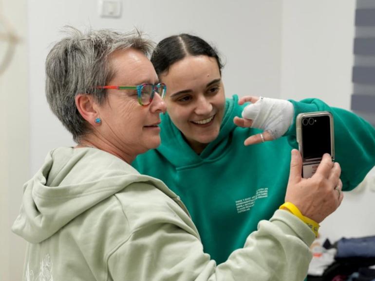 Released hostage Emily Damari (R) embracing her mother Mandy (C) at a reception point near Kibbutz Reim, southern Israel on January 19.