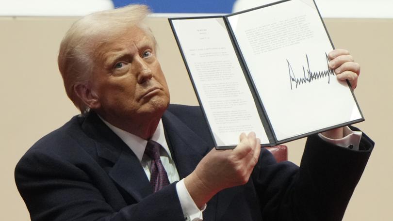 President Donald Trump holds up an executive orders after signing it at an indoor Presidential Inauguration parade event in Washington, Monday, Jan. 20, 2025.