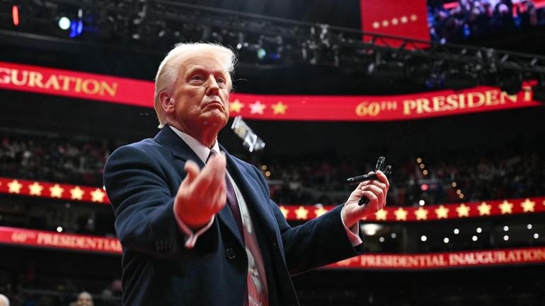 US President Donald Trump throws pens to the crowd after signing executive orders during the inaugural parade inside Capital One Arena.