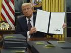 President Donald Trump holds up an executive order commuting sentences for people convicted of January 6 offences.