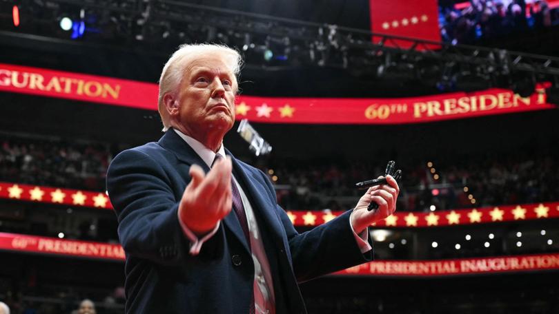 US President Donald Trump throws pens to the crowd after signing executive orders during the inaugural parade inside Capital One Arena, in Washington, DC.