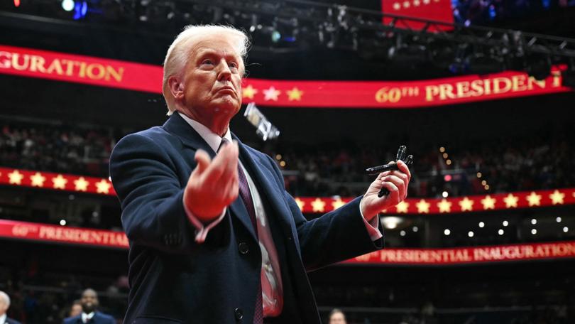 US President Donald Trump throws pens to the crowd after signing executive orders during the inaugural parade inside Capital One Arena.