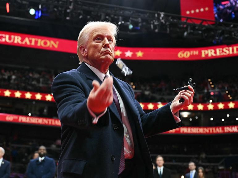 US President Donald Trump throws pens to the crowd after signing executive orders during the inaugural parade inside Capital One Arena.