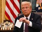 US President Donald Trump holds up outgoing President Joe Biden's letter as he signs executive orders in the Oval Office of the WHite House in Washington, DC, on January 20, 2025. (Photo by Jim WATSON / POOL / AFP) / ALTERNATE CROP