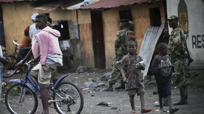 Children walk past M23 rebels in the eastern Congo town of Sake.