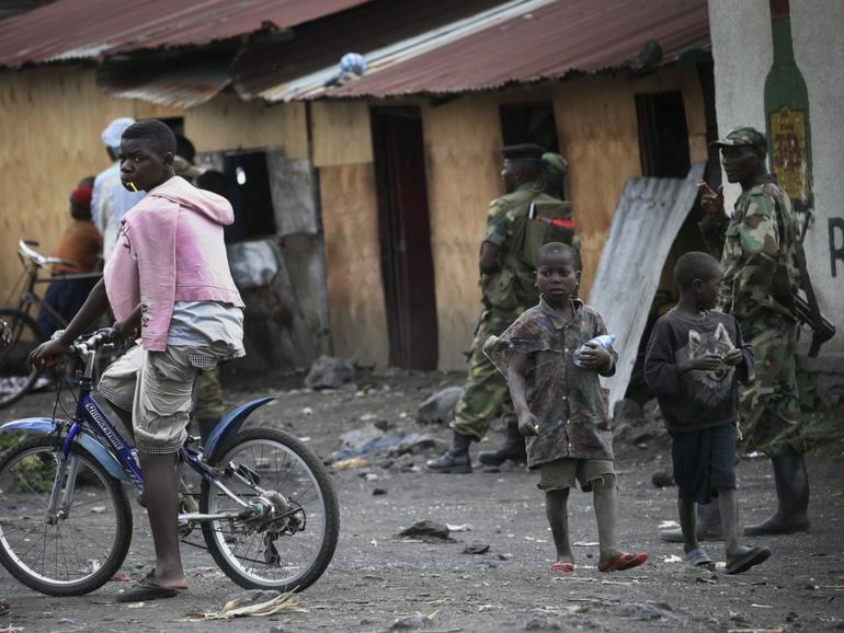 Children walk past M23 rebels in the eastern Congo town of Sake.