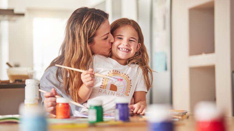 Mother, child and painting art in home using paint brush for creative activity for learning, bonding and love between mom and daughter. Woman or parent give girl kid kiss for creativity in USA house.